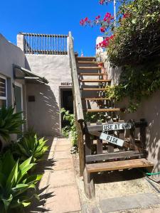 a wooden bench with a sign on it next to a building at Cozy Crner Kitehouse in Langebaan