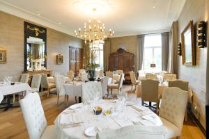 un restaurant avec des tables et des chaises blanches et un lustre dans l'établissement Hof de Draeck Bed & Breakfast, à Teuven