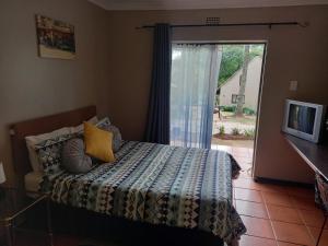 1 dormitorio con 1 cama y puerta corredera de cristal en Little Rock Resort en Ladybrand