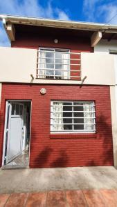 une maison en briques rouges avec une porte blanche dans l'établissement Acacias, à Mar de Ajó