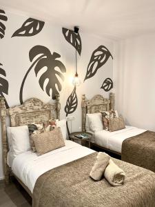 two beds in a room with palm trees on the wall at Hostal El Caprichito Marbella in Marbella