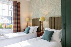 two beds in a room with a window at The Richard Onslow in Cranleigh
