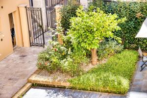 un giardino con un albero e alcuni cespugli e fiori di Giardino dei Lenti - Self check-in Apartments a Bari