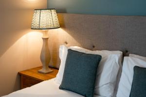 a bed with a lamp on a table next to it at The Richard Onslow in Cranleigh