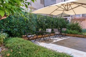 eine Terrasse mit einem Tisch, Stühlen und einem Sonnenschirm in der Unterkunft Giardino dei Lenti - Self check-in Apartments in Bari