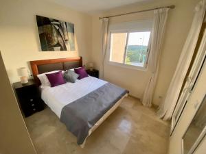 a bedroom with a bed with purple pillows and a window at Townhouse in Manilva in Manilva