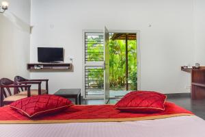 a bedroom with a bed with red pillows and a television at Clover Holiday Village in Madikeri
