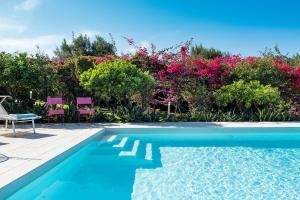 a swimming pool with two chairs and pink flowers at Il Giardino Ritrovato in Marsala