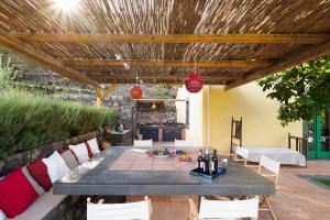 patio con tavolo e sedie sotto un soffitto in legno di Nerello Mascalese a Montelaguardia