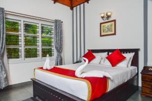 a bedroom with a large bed with red and white pillows at Clover Holiday Village in Madikeri