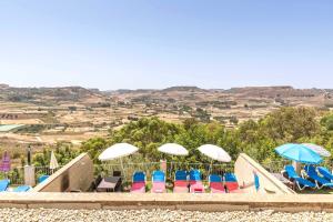 eine Gruppe von Stühlen und Sonnenschirmen am Strand in der Unterkunft Ta Guljetta 4 bedroom Villa with private pool in Marsalforn