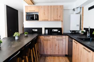 una cocina con armarios de madera y encimeras negras en Les Anémones en Les Orres