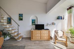 een woonkamer met een tv op een dressoir en een trap bij Casa de Mar in Moncarapacho