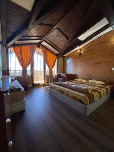 two beds in a room with wooden floors and windows at Хотел-механа Добърско in Dobărsko