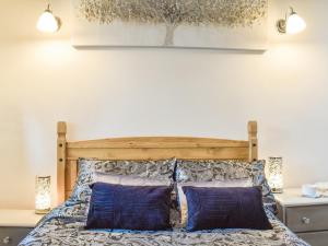 a bedroom with a wooden bed with two blue pillows at Weavers Cottage in Holmfirth