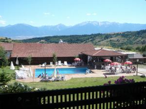 a resort with a swimming pool and mountains in the background at Хотел-механа Добърско in Dobărsko