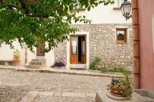 Casa de piedra con puerta marrón y acera de piedra en Baglio Maranzano - Titi, en Buseto Palizzolo