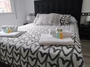 Una cama con dos toallas y dos bebidas. en Apartamento GIJON LOS CAMPOS, en Gijón