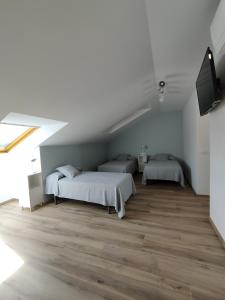 a bedroom with two beds and a flat screen tv at Pensión Residencial Platas in O Pedrouzo