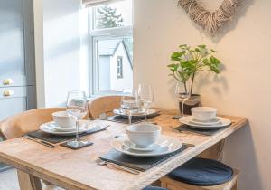 einen Holztisch mit Tellern und Weingläsern darauf in der Unterkunft Victoria Apartment, Derwent House in Keswick