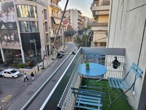 een balkon met een blauwe tafel en stoelen en een straat bij F23 in Athene