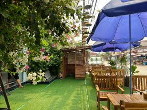 a patio with a blue umbrella and wooden tables and chairs at Confetti Garden Resort in Vang Vieng