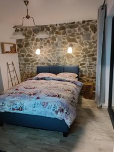 una camera con letto blu di fronte a un muro di pietra di Cabana de pe Stanca a Colibiţa