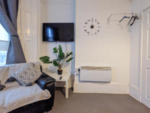 a living room with a couch and a clock on the wall at 1 Bedroom Studio in a Supurb Area of Cardiff in Cardiff
