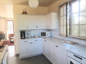 a kitchen with white cabinets and a microwave at LES CIGALINES Chalet au calme in Fabrezan +14 photos