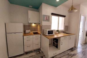 una piccola cucina con elettrodomestici bianchi e una finestra di Bonito apartamento en 2º línea de playa & parking a Málaga