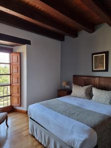 - une chambre avec un grand lit et une fenêtre dans l'établissement Posada Torre Palacio La Taxuela, à Villanueva la Lastra