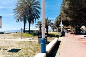 un palo della luce blu su una spiaggia con palme di Bonito apartamento en 2º línea de playa & parking a Málaga