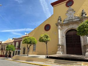 a yellow building with trees in front of it at Apartamento Duplex El Porche in Paradas
