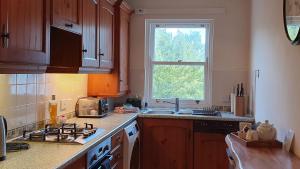 a kitchen with a stove and a sink and a window at Skiddaw. 20 Greta Grove House in Keswick