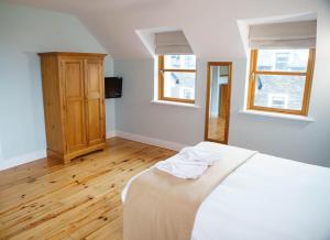1 dormitorio con 1 cama blanca y 2 ventanas en Dingle Courtyard Cottages 4 Bed en Dingle