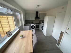a kitchen with a wooden table and a refrigerator at Gatwick Studio in Horley