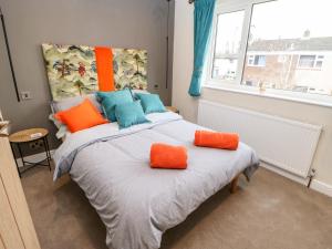 1 dormitorio con 1 cama con almohadas de color naranja y azul en Willows en Corbridge