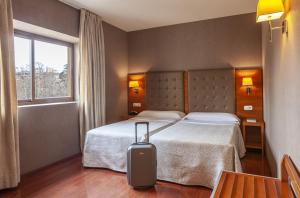 a hotel room with a bed and a suitcase at Hotel Macià Monasterio de los Basilios in Granada