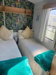 two beds in a small room with green sheets at Sleeps 6 Gym Entertainment Pool Beach in Rhyl