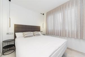 a white bedroom with a large bed and a window at Sunrise Center Suites in Torrevieja
