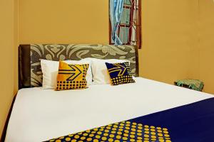 a bed with yellow and blue pillows on it at SPOT ON 92450 Homestay Simpang Panji Suroso Syariah in Malang