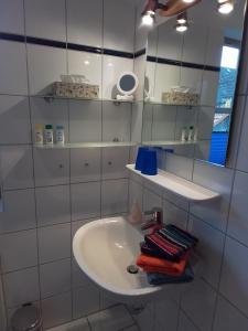 W białej łazience znajduje się umywalka i lustro. w obiekcie Ferienwohnung Delfs w mieście Hamdorf
