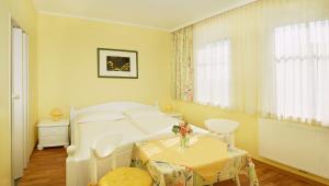 ein weißes Schlafzimmer mit einem Bett und einem Tisch in der Unterkunft Gästezimmer Helga Sommer in Mörbisch am See