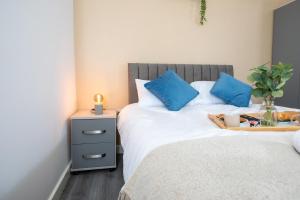 Una cama con almohadas azules y una bandeja de comida. en Charming 1BR in Stockport Center en Stockport