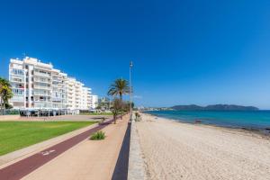 una playa de arena con palmeras y un edificio en Apto con Terraza 202, en Cala Millor