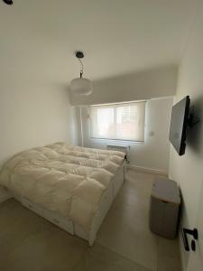 a white bedroom with a bed and a window at Departamento frente al mar in Mar del Plata