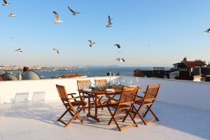 un tavolo e sedie su un tetto con uccelli che volano sopra di noi di Cihangir VAV Suites a Istanbul