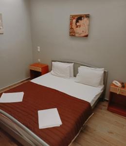 a bedroom with a bed with two white papers on it at Efstratios Hotel in Loutra Edipsou