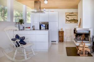 a white kitchen with a chair and a fireplace at Villa Dynni · Villa Dynni - South Facing - Seafront - Jacuzzi in Helsinki