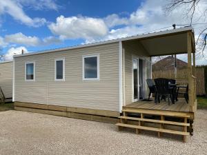 a mobile home with a deck and a table at Camping de Contrexeville in Contrexéville